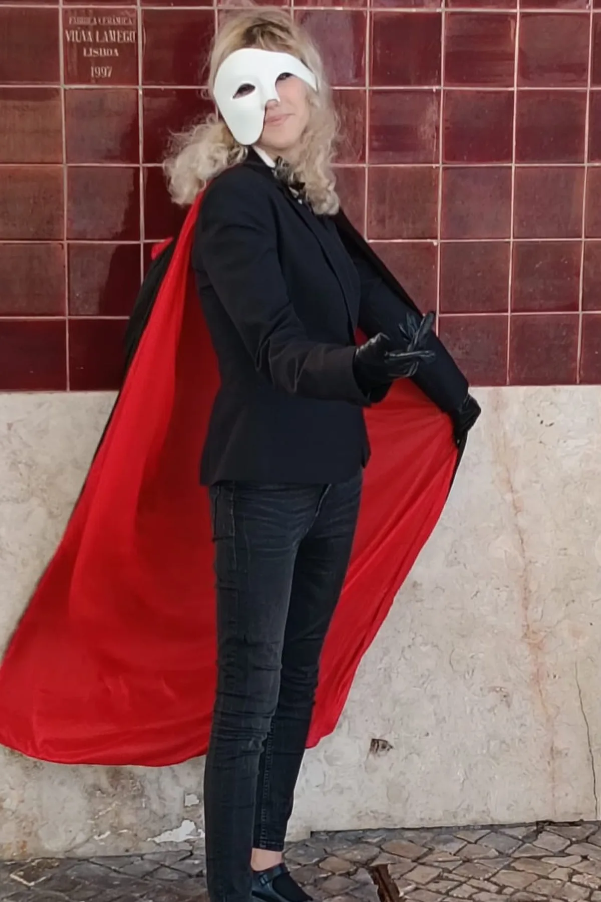 Woman in a black blazer and white half-mask holding a red rose, a phantom of the opera solo Halloween costume