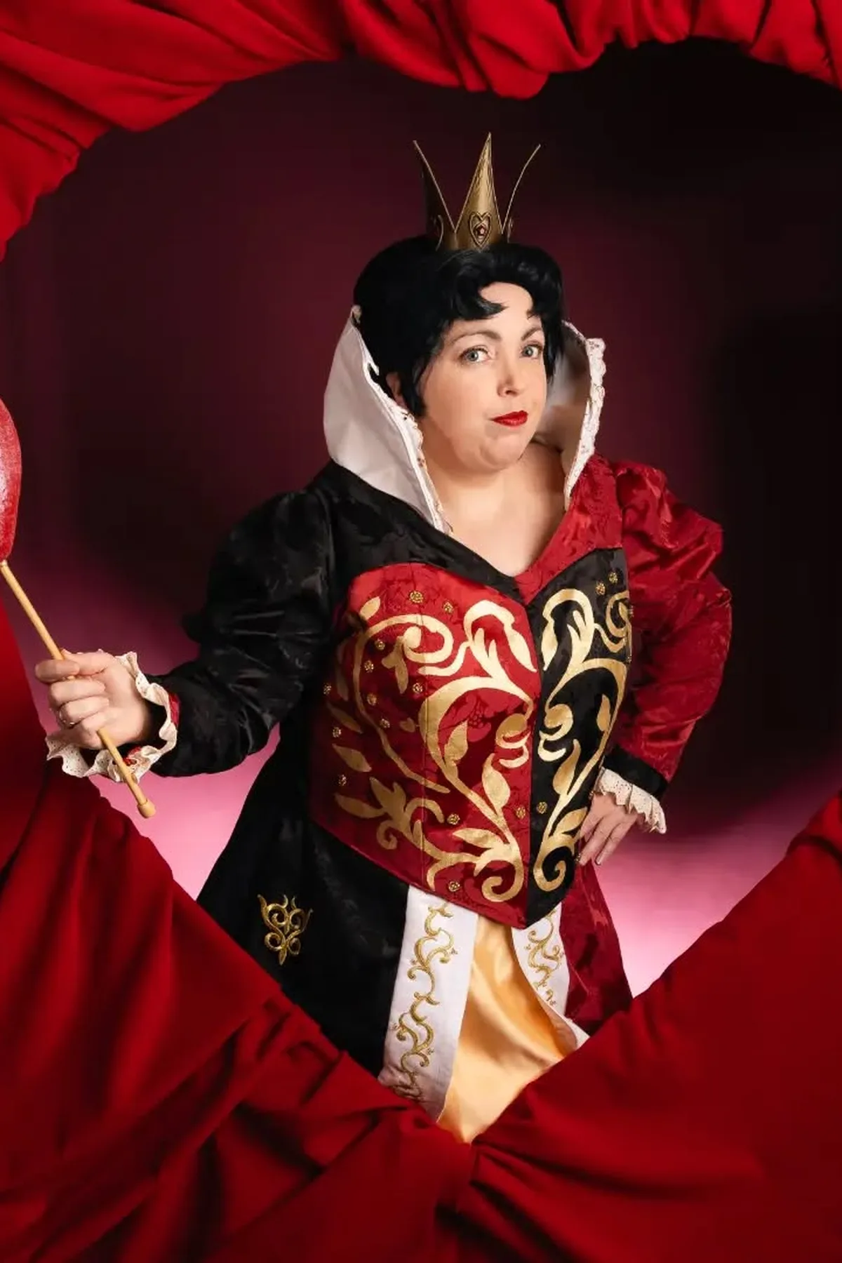 Woman in a red-and-black dress and gold crown with playing cards, a Queen of Hearts solo Halloween costume