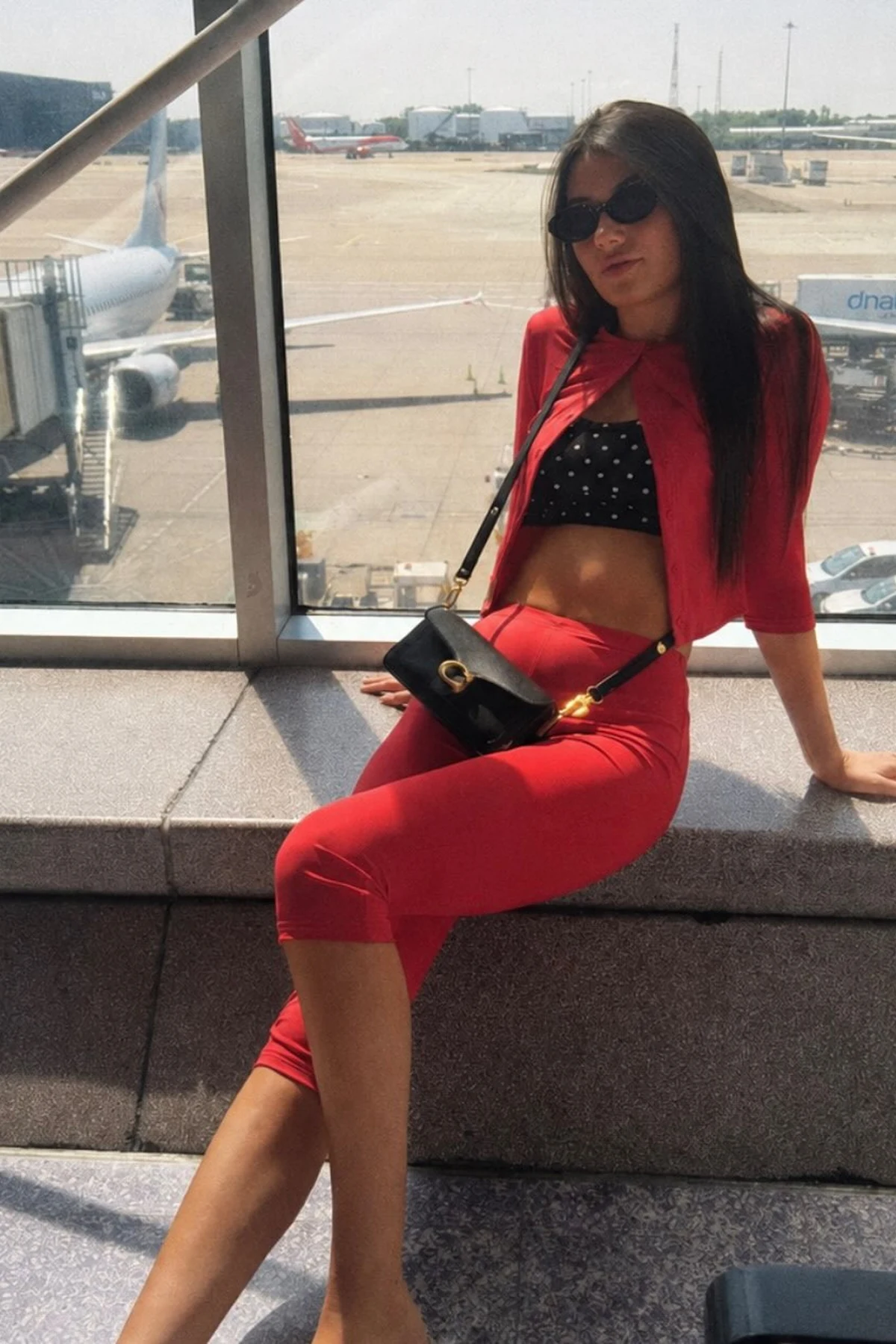 Woman in burgundy cardigan, black top and ponte pants at an airport lounge at Christmas
