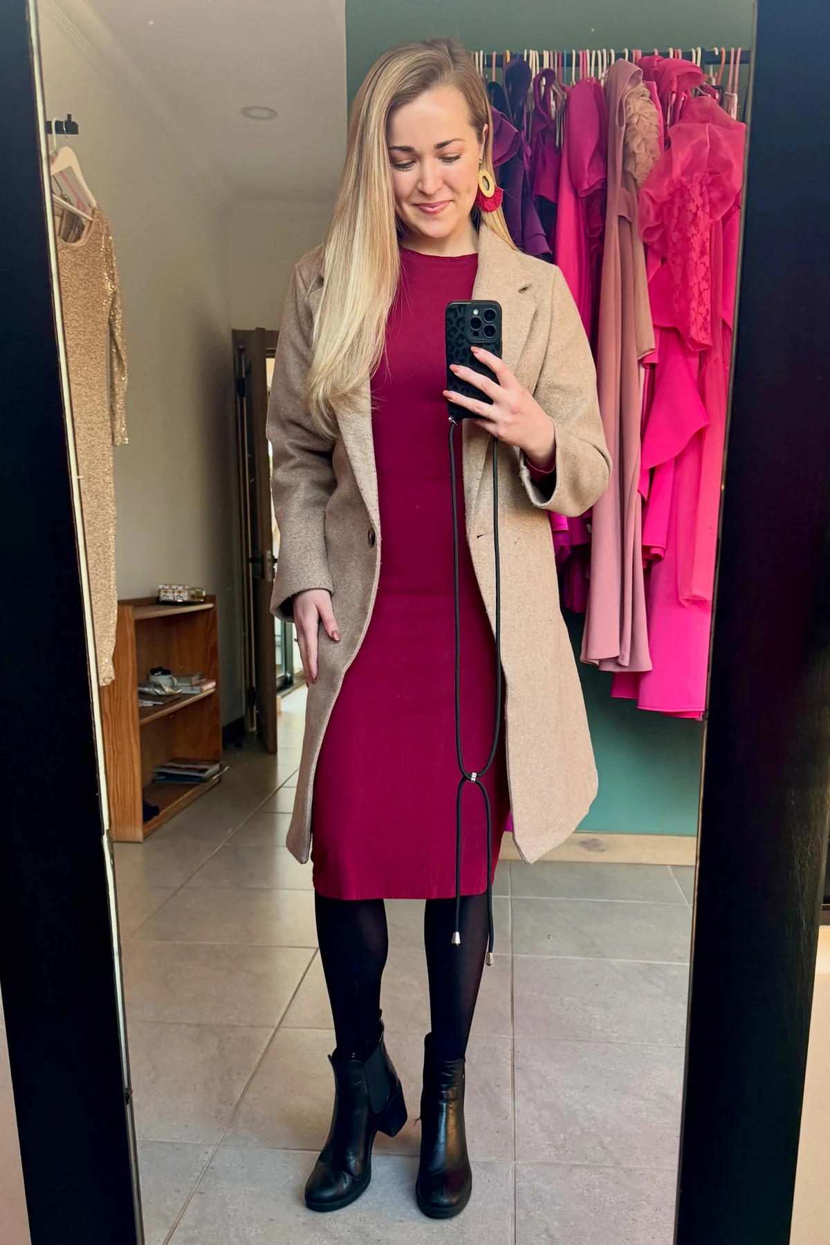 Woman in burgundy knit dress, black tights and ankle boots stepping off a train at Christmas