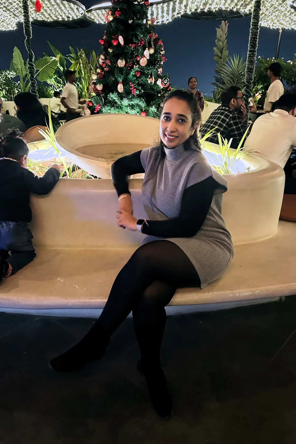 Woman in gray sweater dress, leggings and sneakers waiting for a train at Christmas