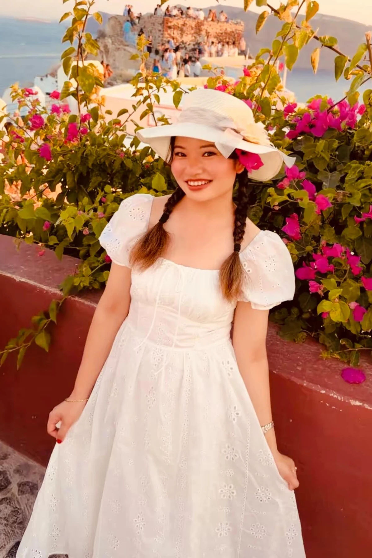 Woman in white eyelet midi dress and gold sandals against a whitewashed wall at Christmas
