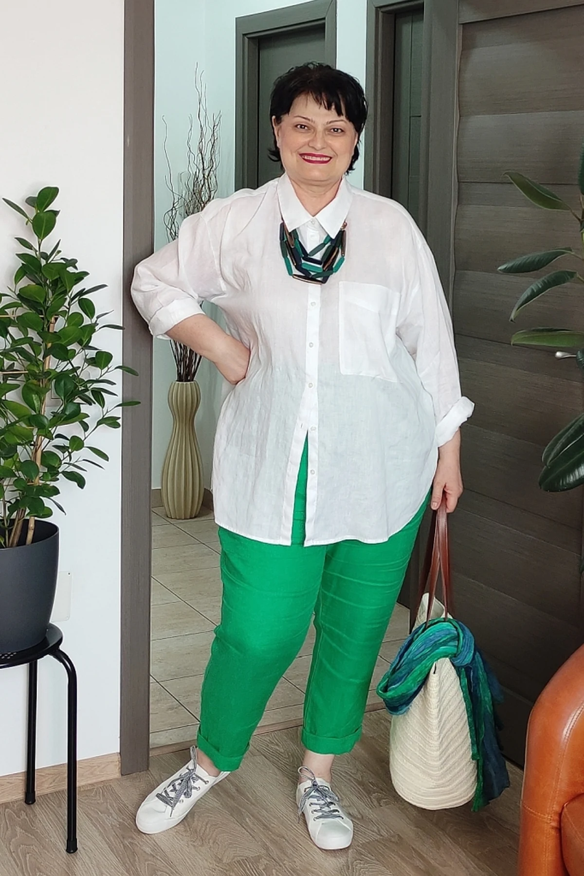 Woman in white linen shirt and olive linen pants carrying a basket at a farmers market