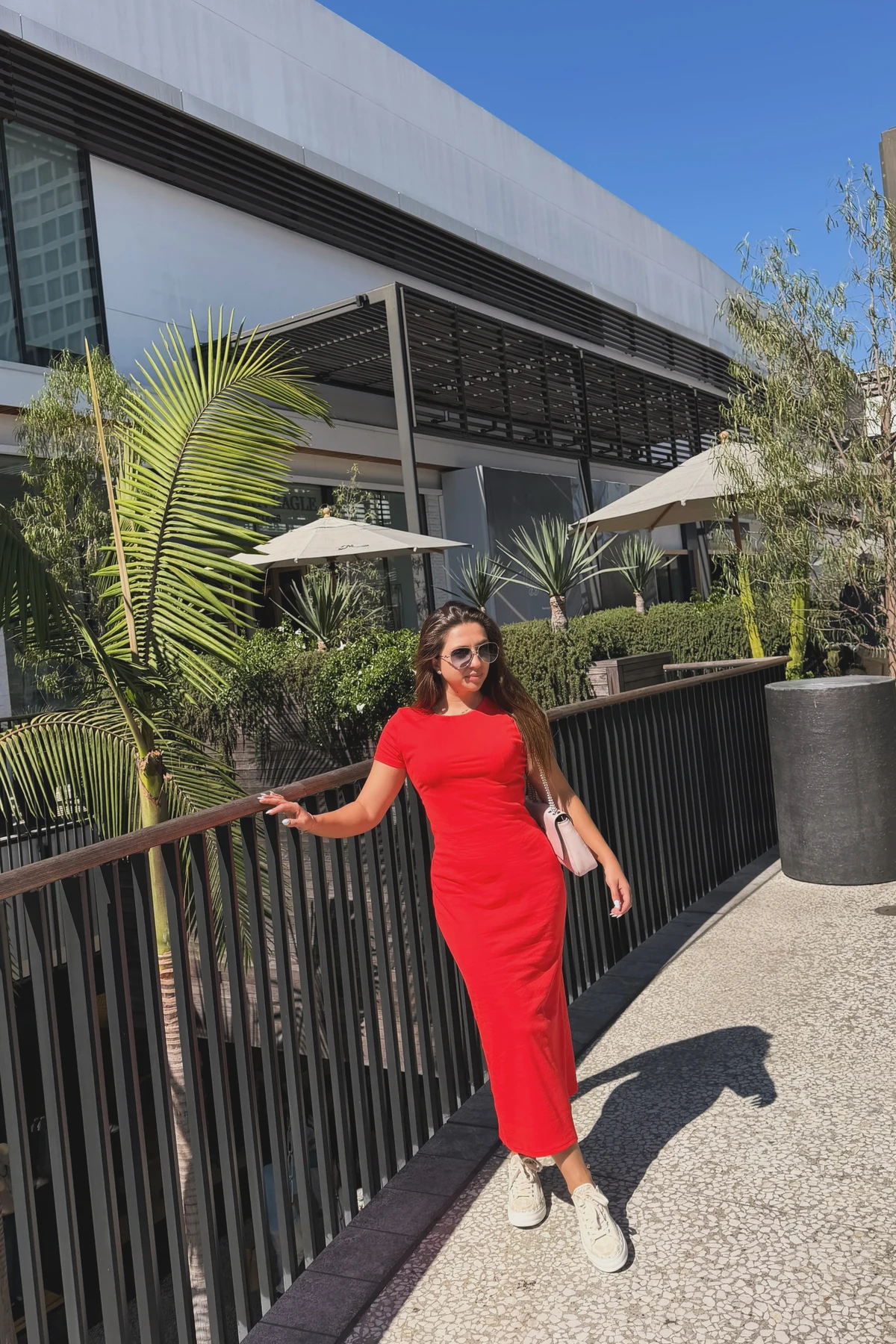 Woman in red cotton midi dress and white sneakers at a sunny outdoor Christmas festival