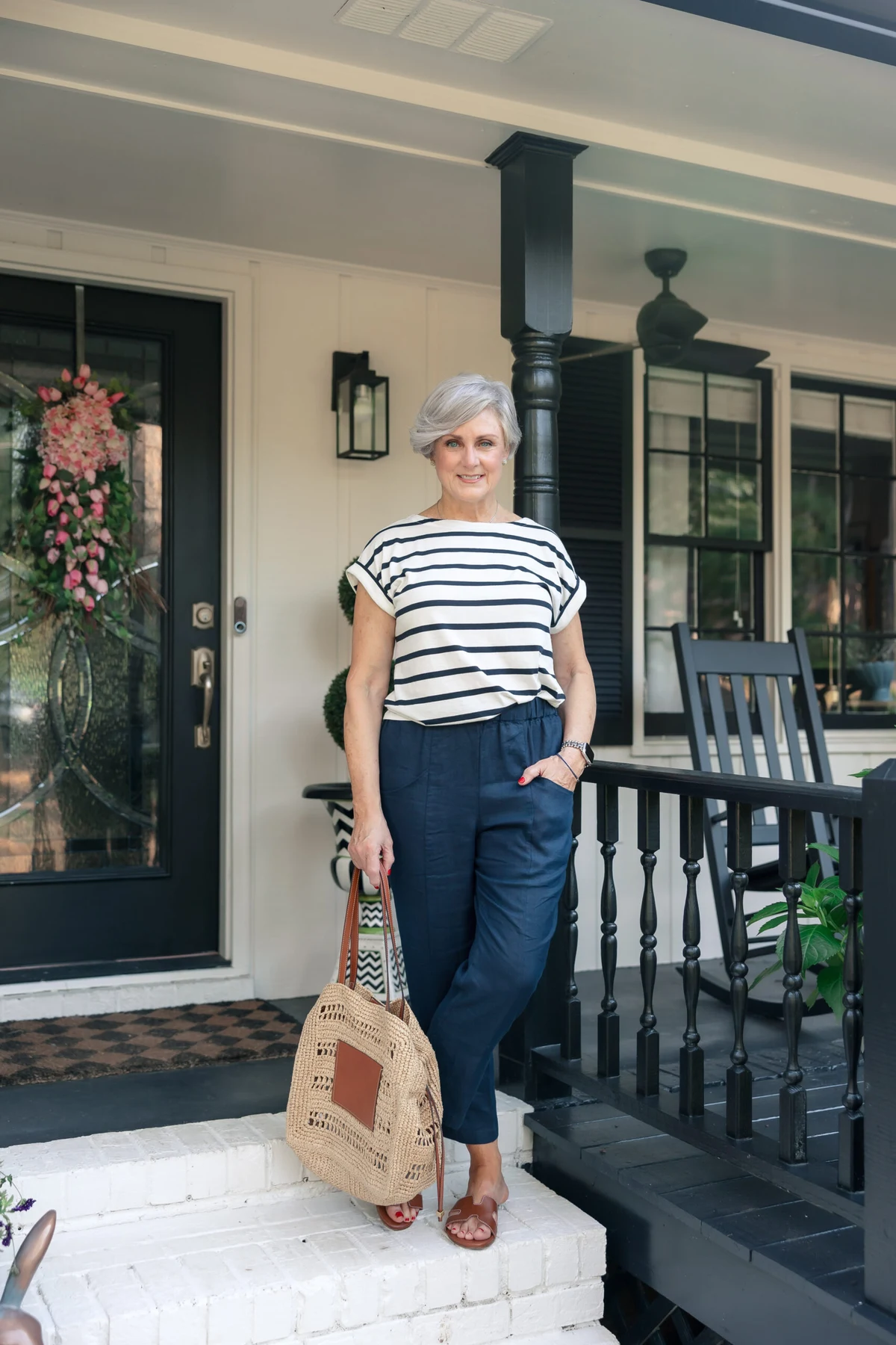 Woman in red-striped tee and navy linen pants walking by a harbor at Christmas