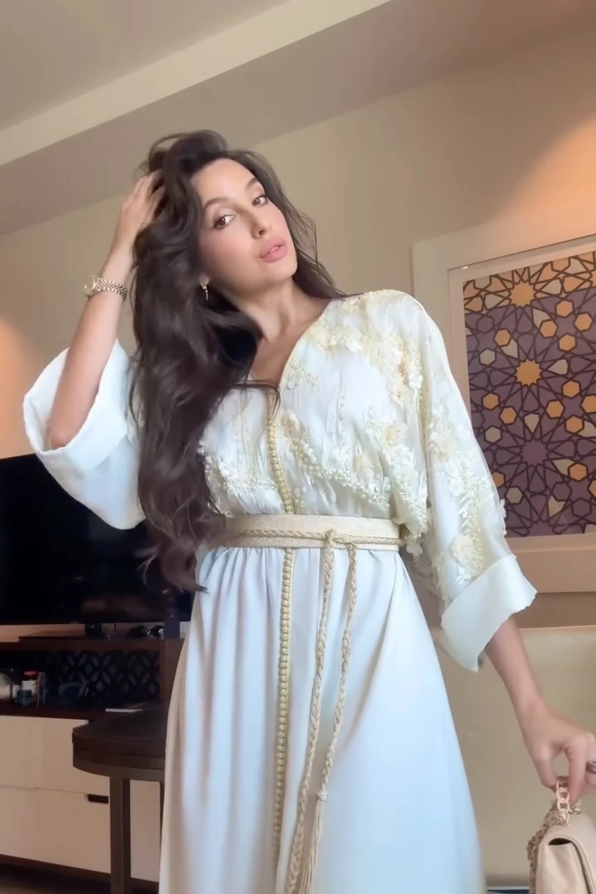 Woman in white and gold embroidered kaftan on a veranda with string lights at Christmas