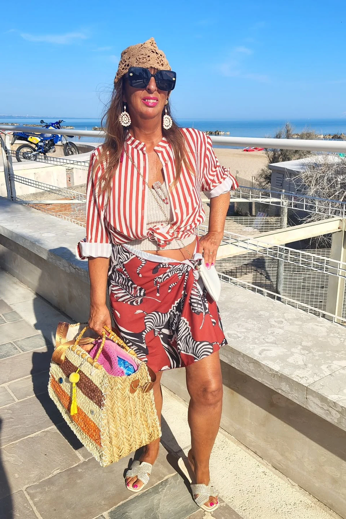 Woman in striped linen top and red cropped trousers at a seaside Christmas market