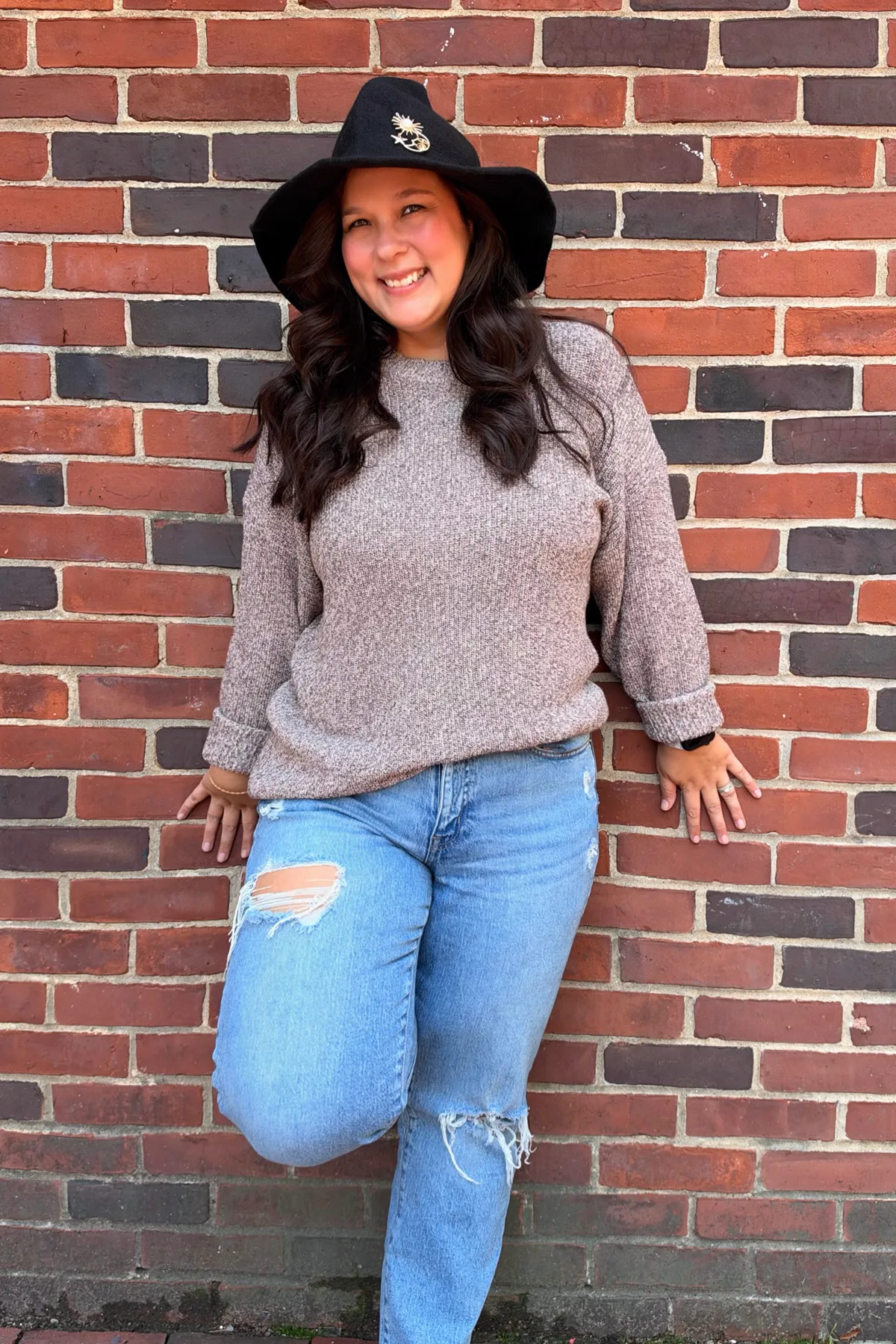 Woman in a teal sweater and dark jeans with a witch hat, a casual plus size witch costume