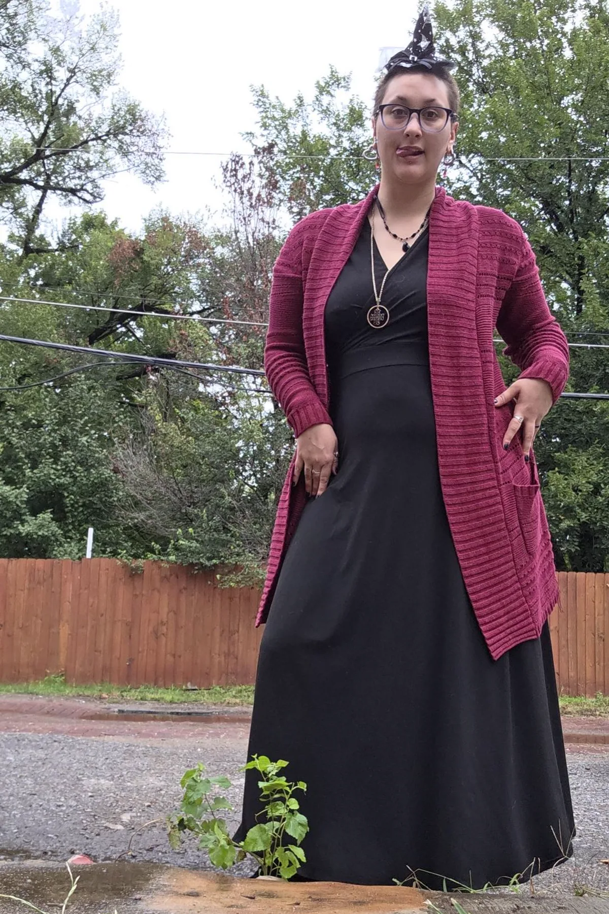 Woman in a red cardigan and black maxi skirt with a pointed hat, a plus size kitchen witch costume